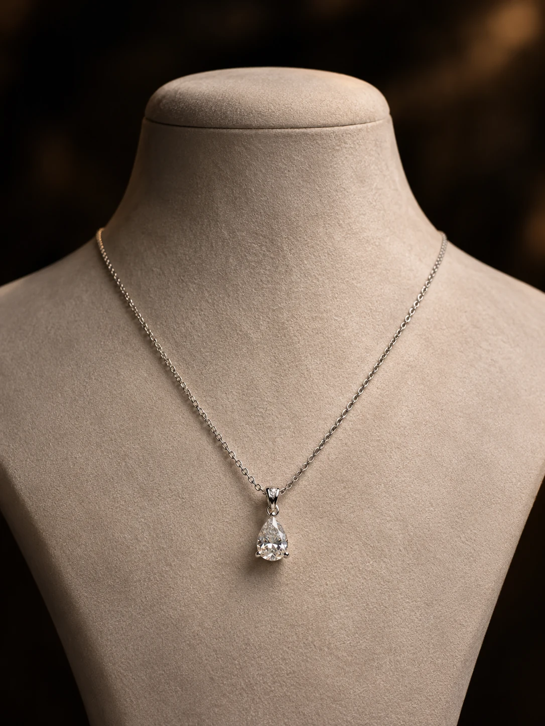Pear-shaped diamond pendant on a fine chain displayed on a pale bust